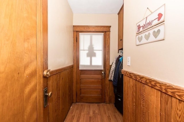 doorway to outside featuring hardwood / wood-style floors and wooden walls