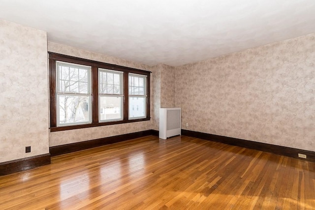 spare room with radiator heating unit and wood-type flooring