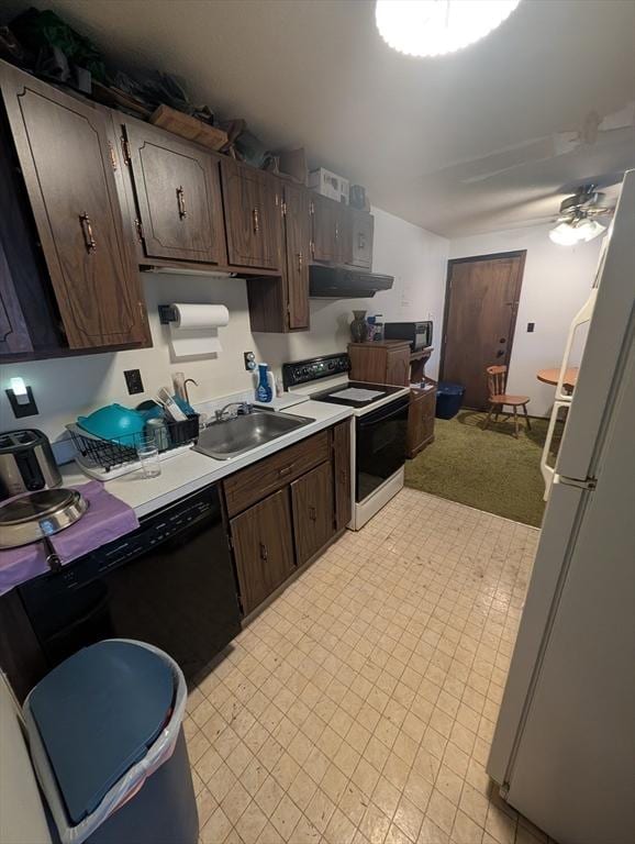 kitchen with black appliances, a sink, under cabinet range hood, light countertops, and dark brown cabinets