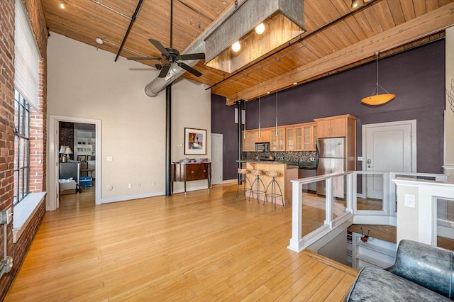 living room with light wood-type flooring, baseboards, wooden ceiling, and a towering ceiling