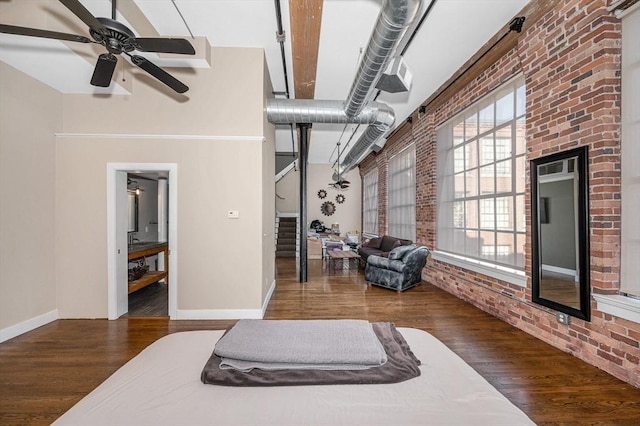 bedroom with wood finished floors, baseboards, and brick wall