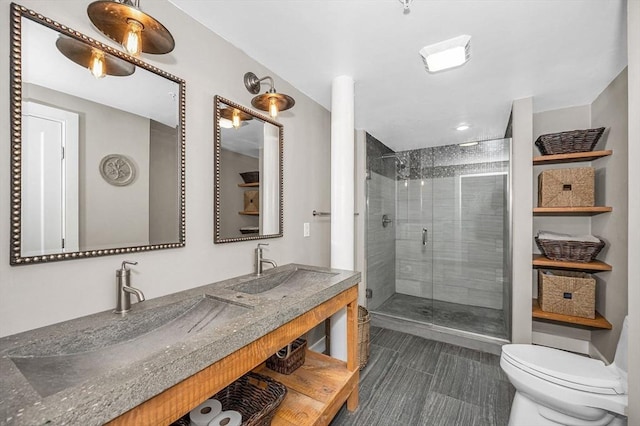 bathroom featuring a shower stall, toilet, double vanity, and a sink