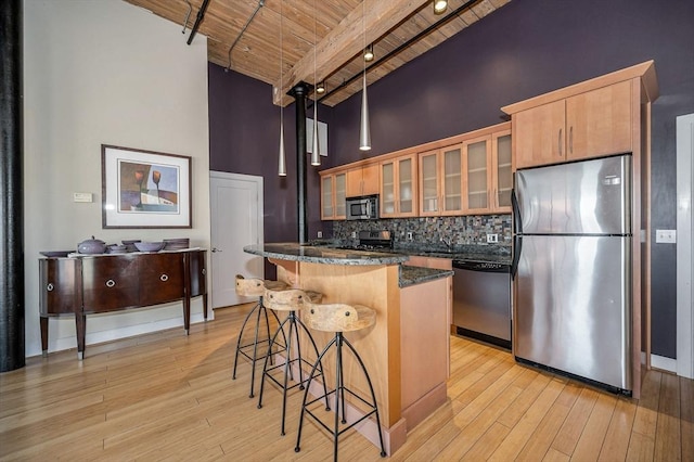 kitchen featuring a breakfast bar area, a high ceiling, light wood-style flooring, and appliances with stainless steel finishes