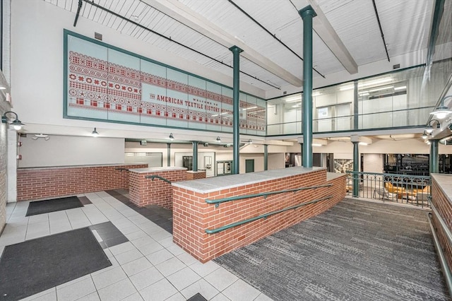 interior space with beam ceiling, brick wall, and tile patterned flooring