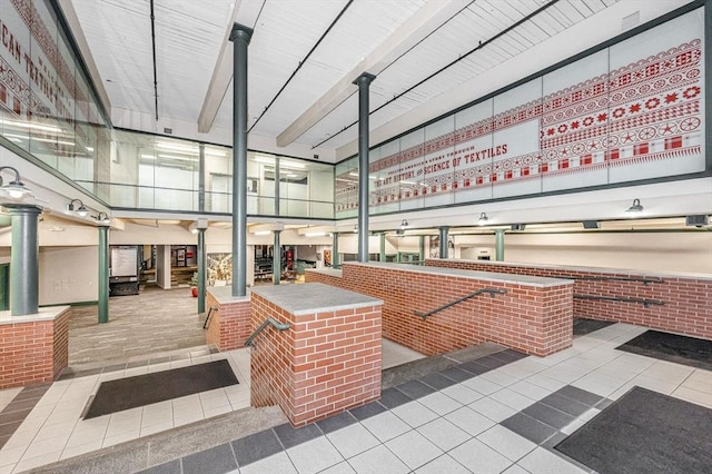 misc room featuring tile patterned floors, beamed ceiling, and brick wall