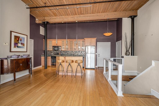 kitchen featuring tasteful backsplash, appliances with stainless steel finishes, a center island, and wooden ceiling