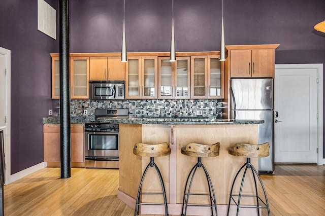 kitchen featuring light wood-style flooring, tasteful backsplash, appliances with stainless steel finishes, and a center island