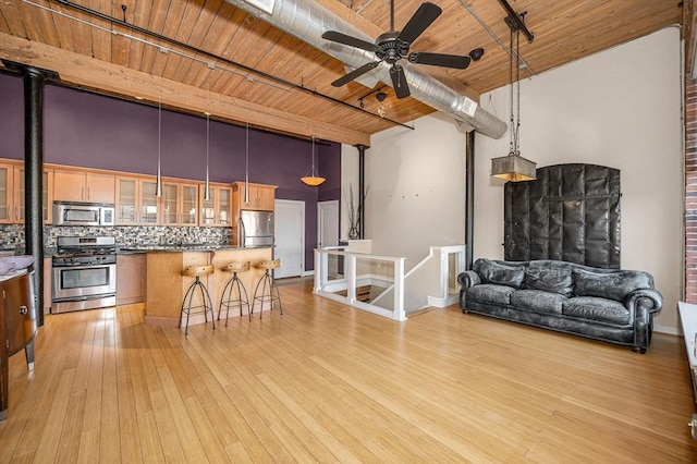 kitchen featuring stainless steel appliances, light wood-style floors, a breakfast bar area, wooden ceiling, and decorative backsplash