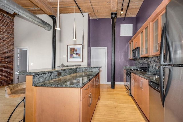 kitchen with a kitchen island, gas range oven, freestanding refrigerator, a high ceiling, and stainless steel dishwasher