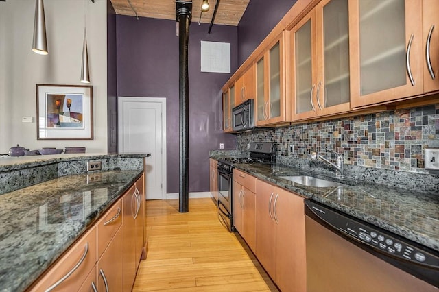 kitchen with brown cabinets, a sink, stainless steel appliances, light wood finished floors, and decorative backsplash