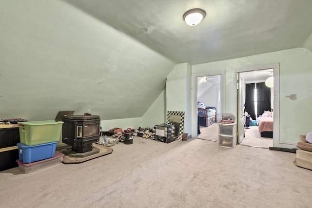 additional living space featuring lofted ceiling, carpet, and a wood stove