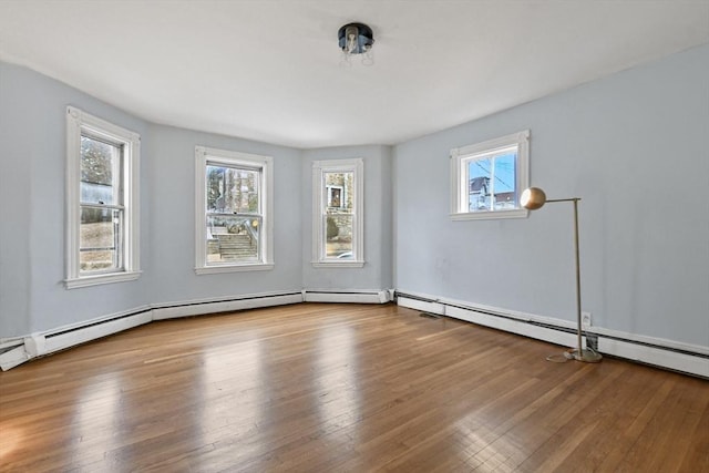 empty room featuring a baseboard heating unit and wood-type flooring