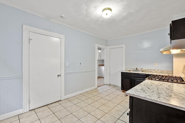 kitchen with a sink, light tile patterned flooring, crown molding, and light countertops