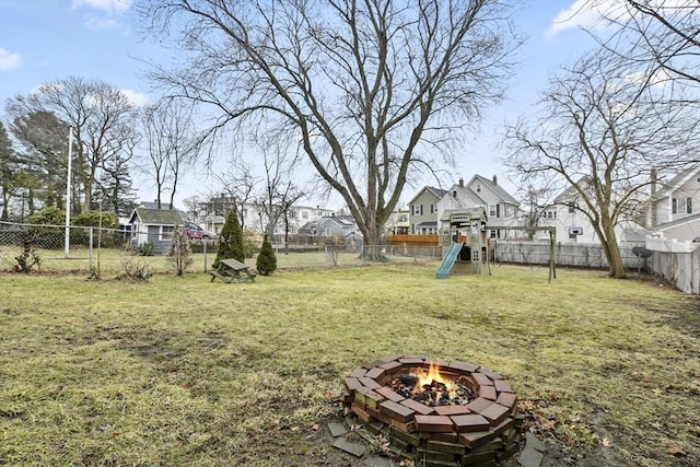 view of yard featuring a residential view, a fire pit, a playground, and a fenced backyard