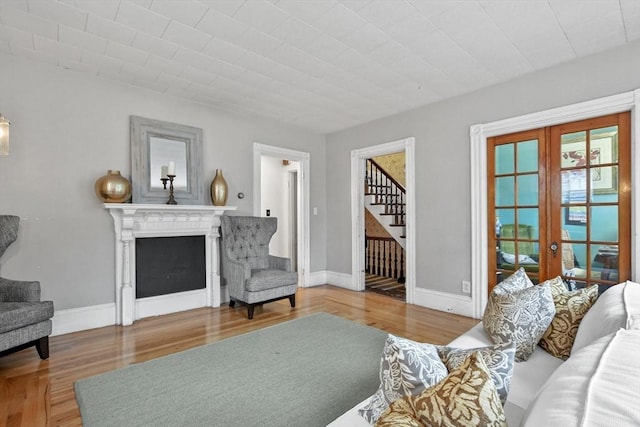 living area with wood finished floors, stairway, a fireplace, and baseboards