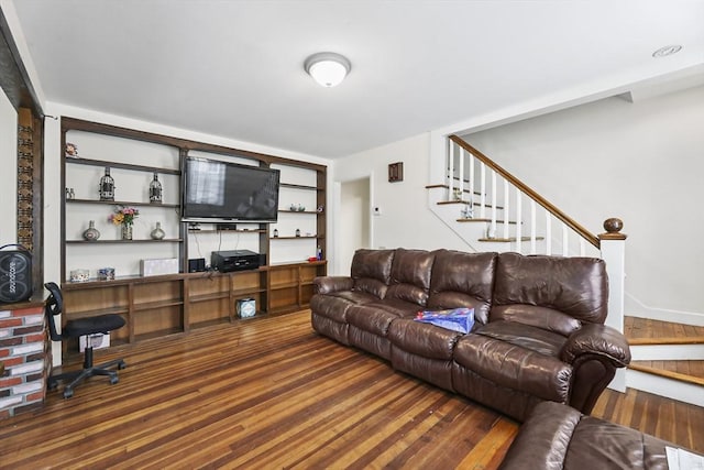 living area featuring built in features, stairway, and wood finished floors