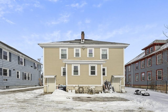 snow covered rear of property featuring a chimney