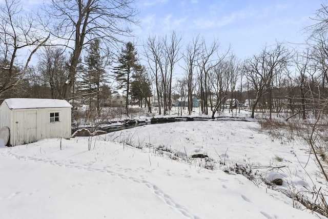 yard layered in snow with a storage shed and an outdoor structure