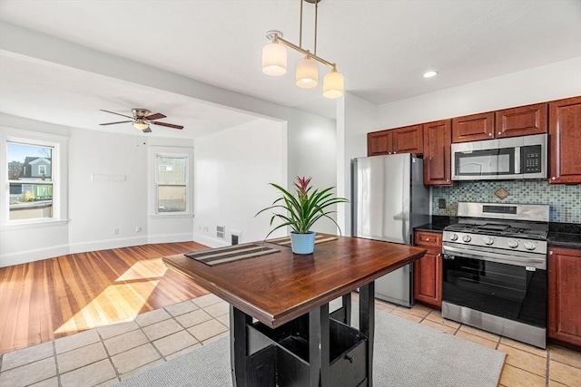 kitchen with ceiling fan, backsplash, pendant lighting, light hardwood / wood-style floors, and appliances with stainless steel finishes