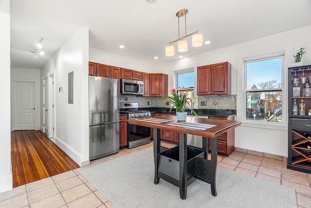 kitchen featuring pendant lighting, a healthy amount of sunlight, stainless steel appliances, and tasteful backsplash