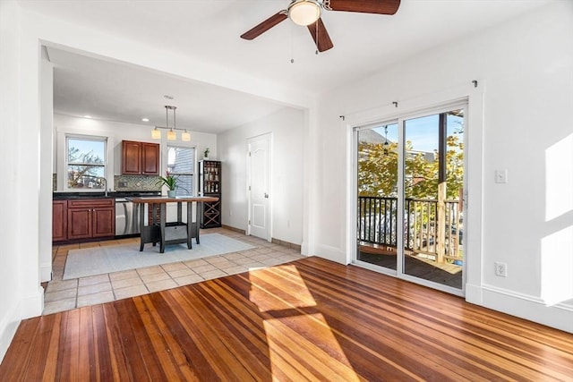 kitchen with tasteful backsplash, dishwasher, pendant lighting, and light hardwood / wood-style flooring