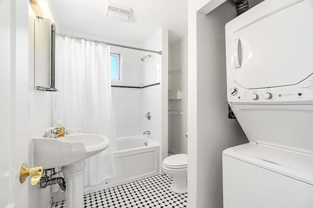 bathroom featuring toilet, stacked washer and dryer, and shower / tub combo with curtain