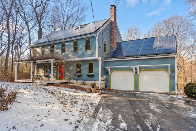 view of front facade with a garage, covered porch, and solar panels