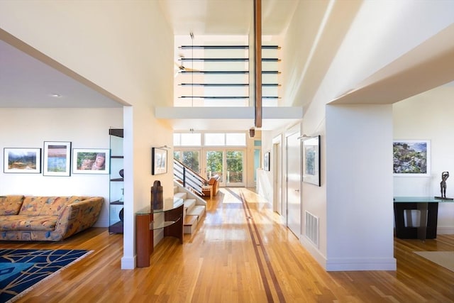 hall with a towering ceiling and hardwood / wood-style floors