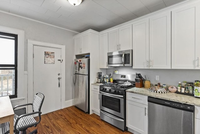 kitchen featuring stainless steel appliances, dark wood-style flooring, white cabinetry, and light stone counters