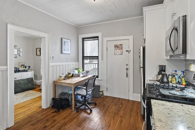 home office featuring a wainscoted wall, a textured wall, dark wood finished floors, and crown molding