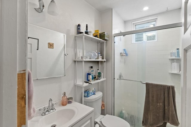 full bathroom featuring a stall shower, vanity, and toilet