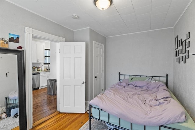 bedroom with light wood-style flooring, ornamental molding, and a sink