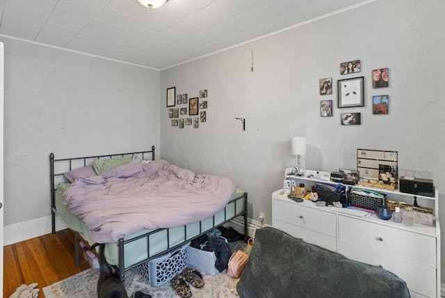 bedroom featuring baseboards, wood finished floors, and ornamental molding