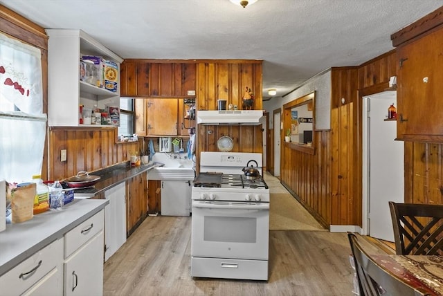 kitchen featuring light wood-type flooring, white appliances, wood walls, and under cabinet range hood