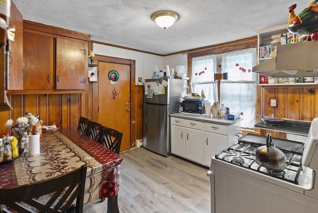 kitchen with white range with gas stovetop, light wood-style floors, freestanding refrigerator, a textured ceiling, and black microwave