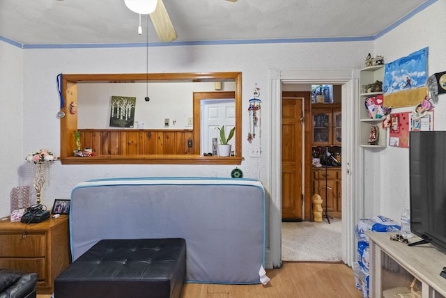 interior space featuring ornamental molding, wood finished floors, and a ceiling fan