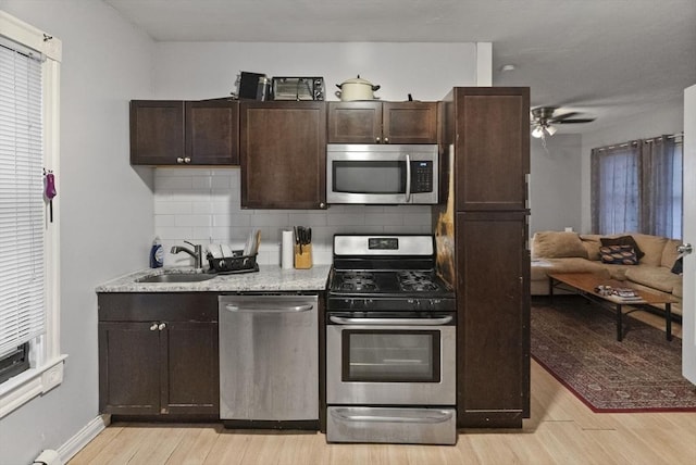 kitchen featuring stainless steel appliances, light wood-type flooring, a sink, and dark brown cabinetry