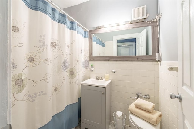 full bathroom with visible vents, a shower with shower curtain, toilet, vanity, and tile walls