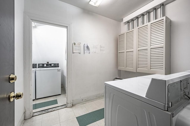 clothes washing area featuring tile patterned flooring, laundry area, and separate washer and dryer