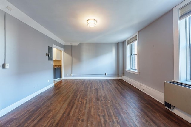 spare room featuring dark wood-style flooring and baseboards