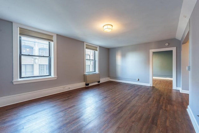 unfurnished room featuring radiator heating unit, dark wood finished floors, and baseboards