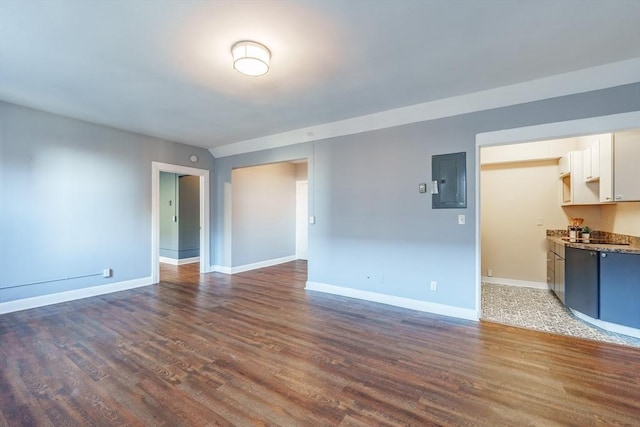 unfurnished living room featuring electric panel, baseboards, and wood finished floors