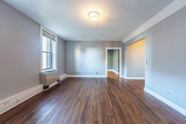 unfurnished room with baseboards and dark wood-type flooring