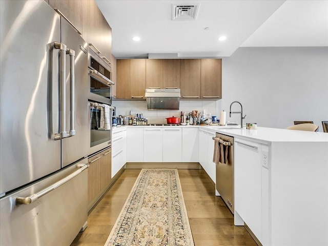 kitchen featuring visible vents, appliances with stainless steel finishes, a peninsula, modern cabinets, and a sink