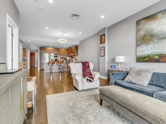 living room with recessed lighting, wood finished floors, visible vents, and baseboards