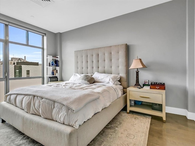 bedroom with visible vents, baseboards, and wood finished floors