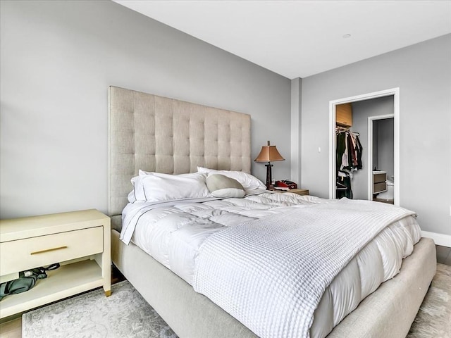 bedroom with a closet, baseboards, and a spacious closet