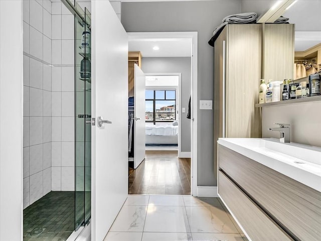 ensuite bathroom featuring a shower stall, baseboards, ensuite bathroom, marble finish floor, and vanity