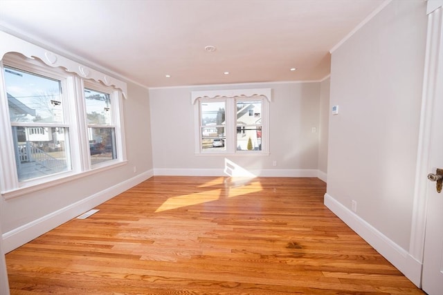 spare room with a healthy amount of sunlight, ornamental molding, and light wood-type flooring