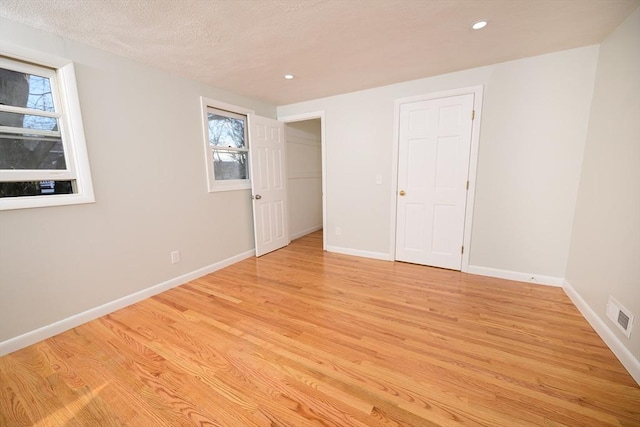 unfurnished bedroom with a textured ceiling and light wood-type flooring